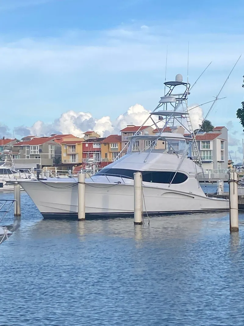 The Image of 2006 Hatteras 54 Convertible yacht docked in a marina with colorful buildings in the background. - 0