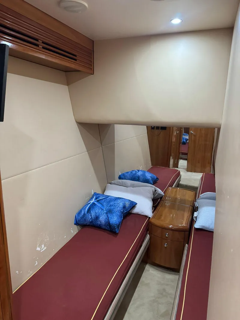 Slide: The Image of 2006 Hatteras 54 Convertible cabin with twin beds, wooden accents, and cozy lighting. - 13