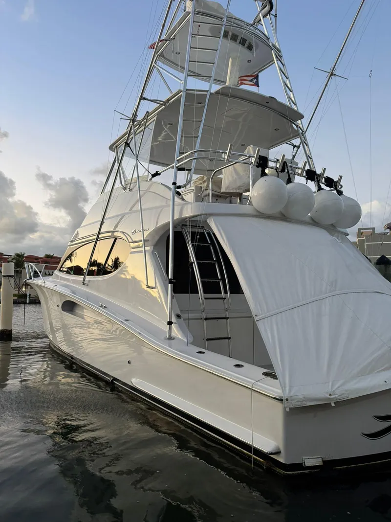 Slide: The Image of 2006 Hatteras 54 Convertible yacht docked at sunset, featuring sleek design and fishing tower. - 3