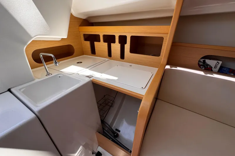 Slide: The Image of Interior of 2014 Beneteau FIRST 25 S sailboat, featuring compact kitchen area with sink and storage. - 26