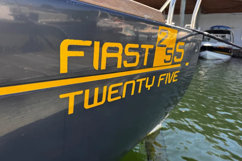 Slide: The Image of 2014 Beneteau FIRST 25 S sailboat with yellow lettering on hull in marina. - 36