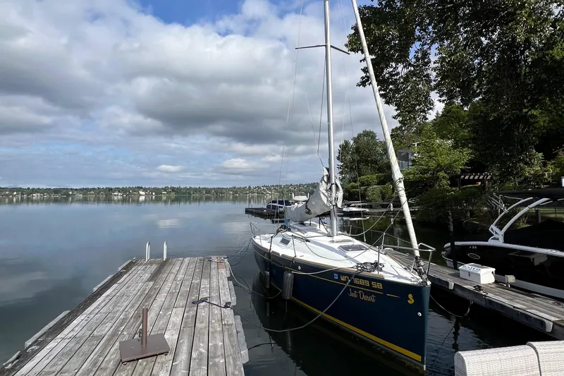 Slide: The Image of Sailboat Beneteau FIRST 25 S, 2014 model, docked on a calm lake under cloudy skies. - 4