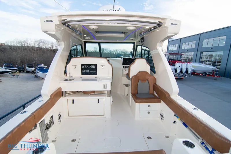 Slide: The Image of 2022 Scout 350 LXZ boat interior with seating and control panel, docked near a marina. - 15