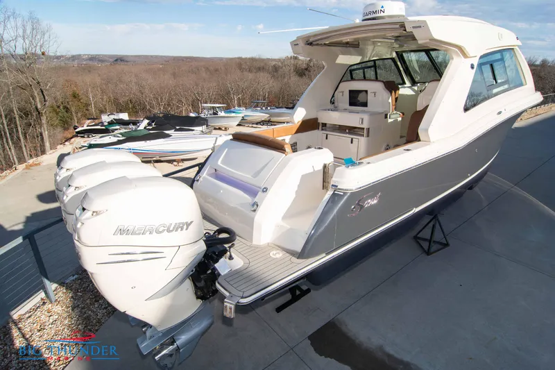 Slide: The Image of 2022 Scout 350 LXZ boat with triple Mercury engines, docked outdoors. - 5