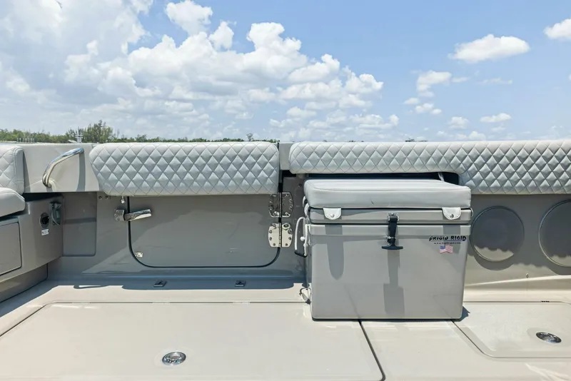 Slide: The Image of 2023 HCB 53 Sueños boat deck with quilted seating and cooler under a cloudy sky. - 25