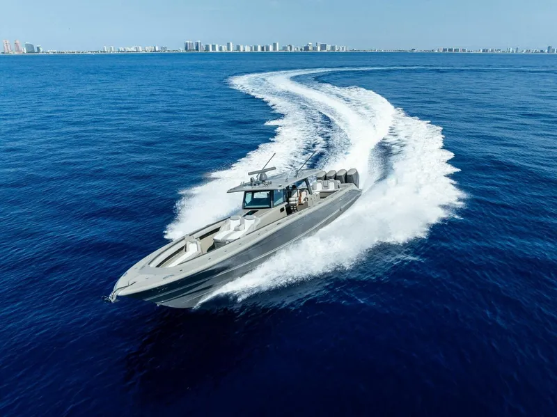 Slide: The Image of 2023 HCB 53 Sueños boat cruising on open blue ocean with city skyline in background. - 38