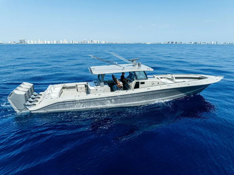 Slide: The Image of 2023 HCB 53 Sueños boat cruising on open blue ocean with city skyline in background. - 39