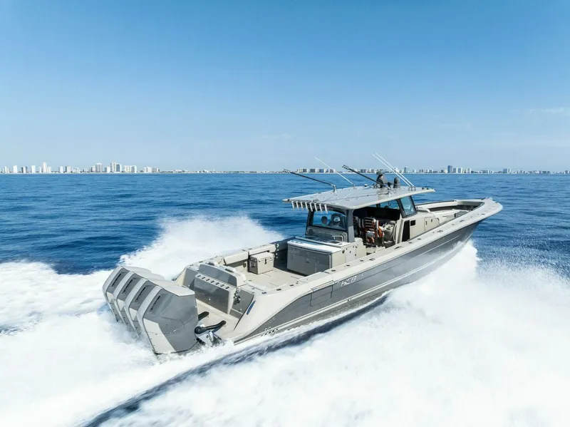 Slide: The Image of 2023 HCB 53 Sueños boat cruising on open water with city skyline in background. - 42