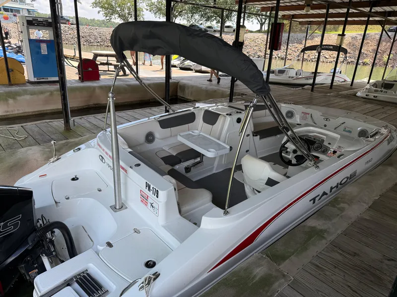 Slide: The Image of 2021 Tahoe 1950 boat docked, featuring a sleek design and spacious interior under a canopy. - 5