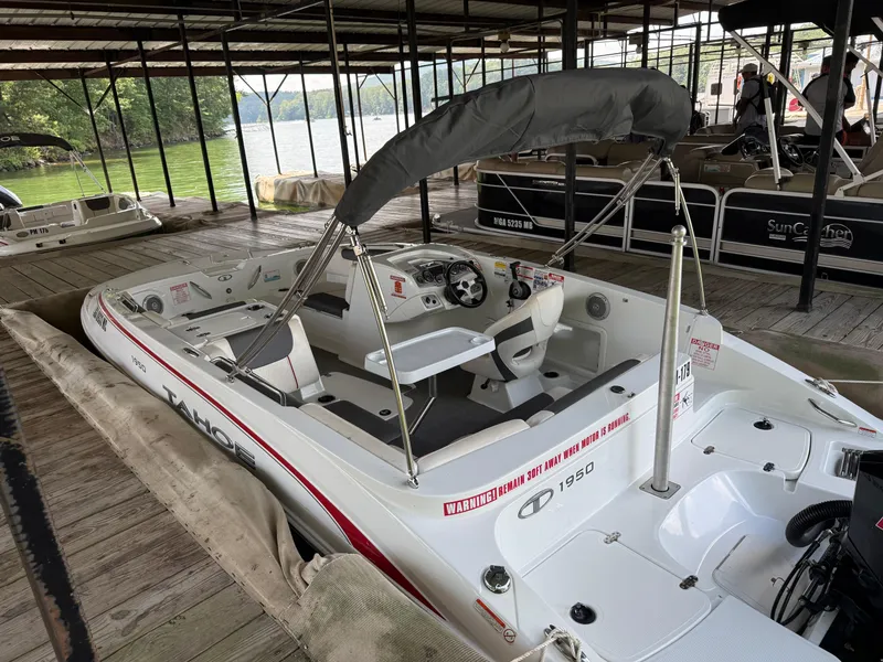 Slide: The Image of Tahoe 1950 boat docked, 2021 model, with canopy and steering wheel, at a lakeside marina. - 6