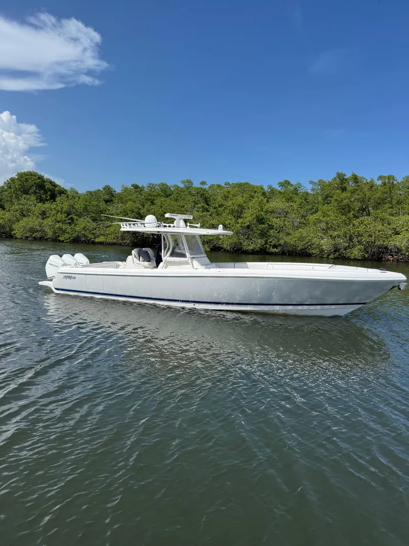 The Image of 2015 Intrepid 375 Center Console boat cruising on a sunny day near lush greenery. - 0