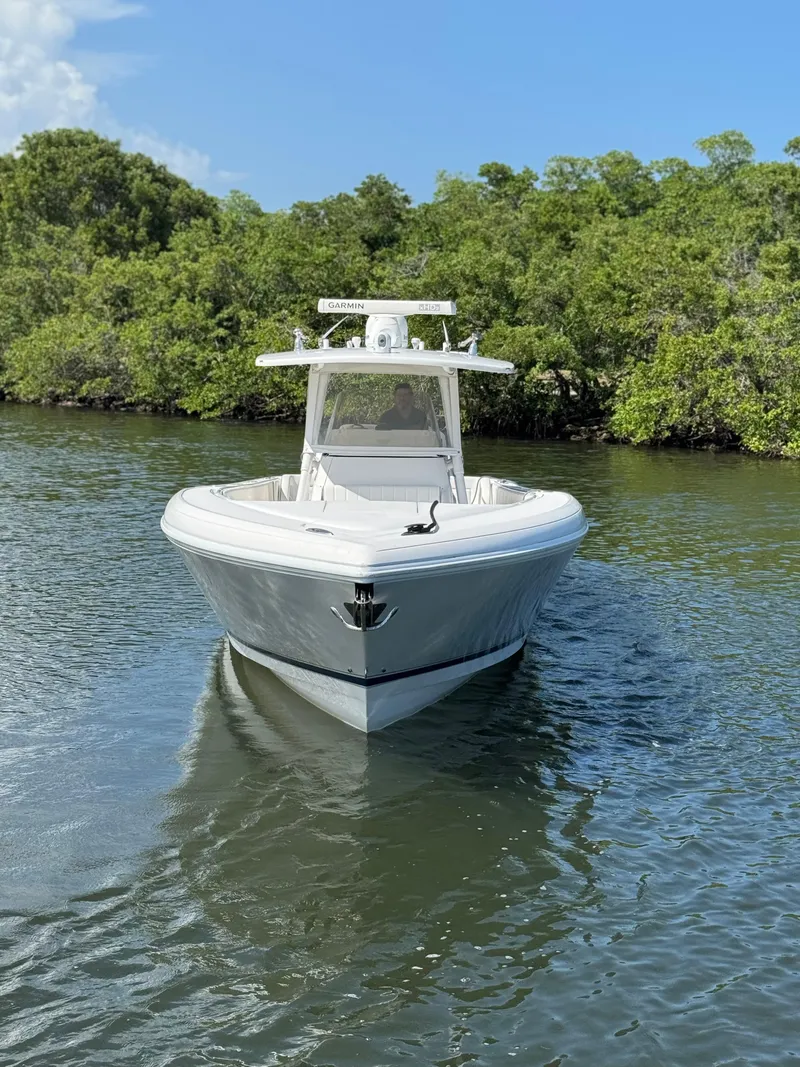 Slide: The Image of 2015 Intrepid 375 Center Console boat on calm water, surrounded by lush greenery. - 17