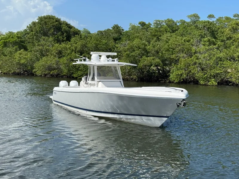 Slide: The Image of 2015 Intrepid 375 Center Console boat on calm water, surrounded by lush greenery. - 18