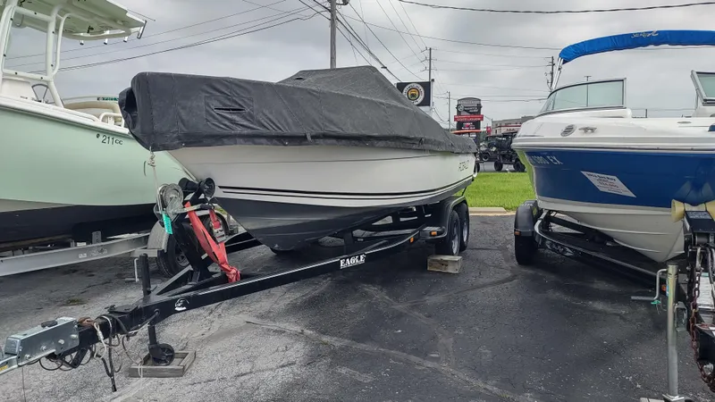 The Image of Robalo 2020 Center Console boat, 2001 model, covered and on trailer, parked between other boats. - 0