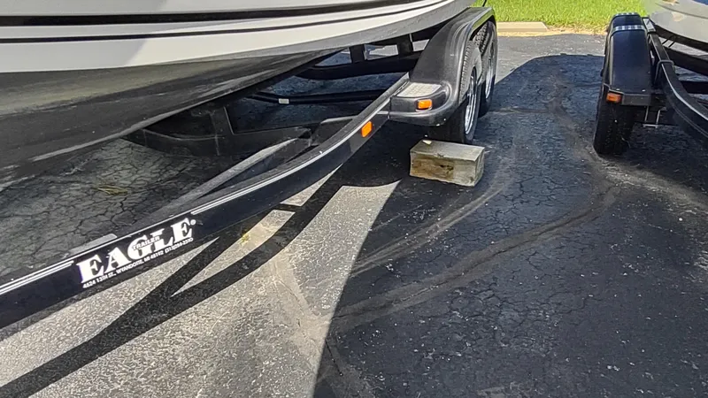 Slide: The Image of Robalo 2020 Center Console boat on Eagle trailer, parked on asphalt with wooden block support. - 14
