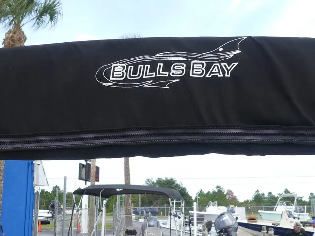 Slide: The Image of A black boat canopy with the "Bulls Bay" logo. Boats and trees are visible in the background. - 28