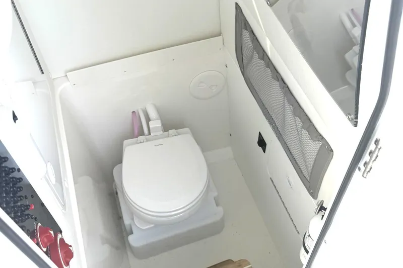 Slide: The Image of 2021 Regulator 25 boat interior with compact marine toilet and storage compartment. - 12