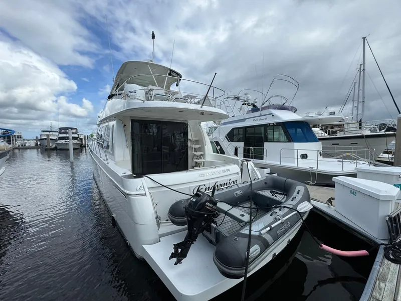 Slide: The Image of 2006 Carver 56 Voyager yacht docked at marina, featuring inflatable boat on stern. - 3
