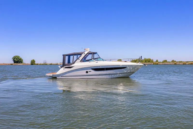 Slide: The Image of 2014 Sea Ray 350 Sundancer cruising on a calm lake under a clear blue sky. - 1