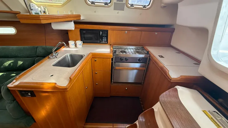 Slide: The Image of 2002 Hunter 326 yacht kitchen with wood cabinetry, sink, stove, and microwave. - 15