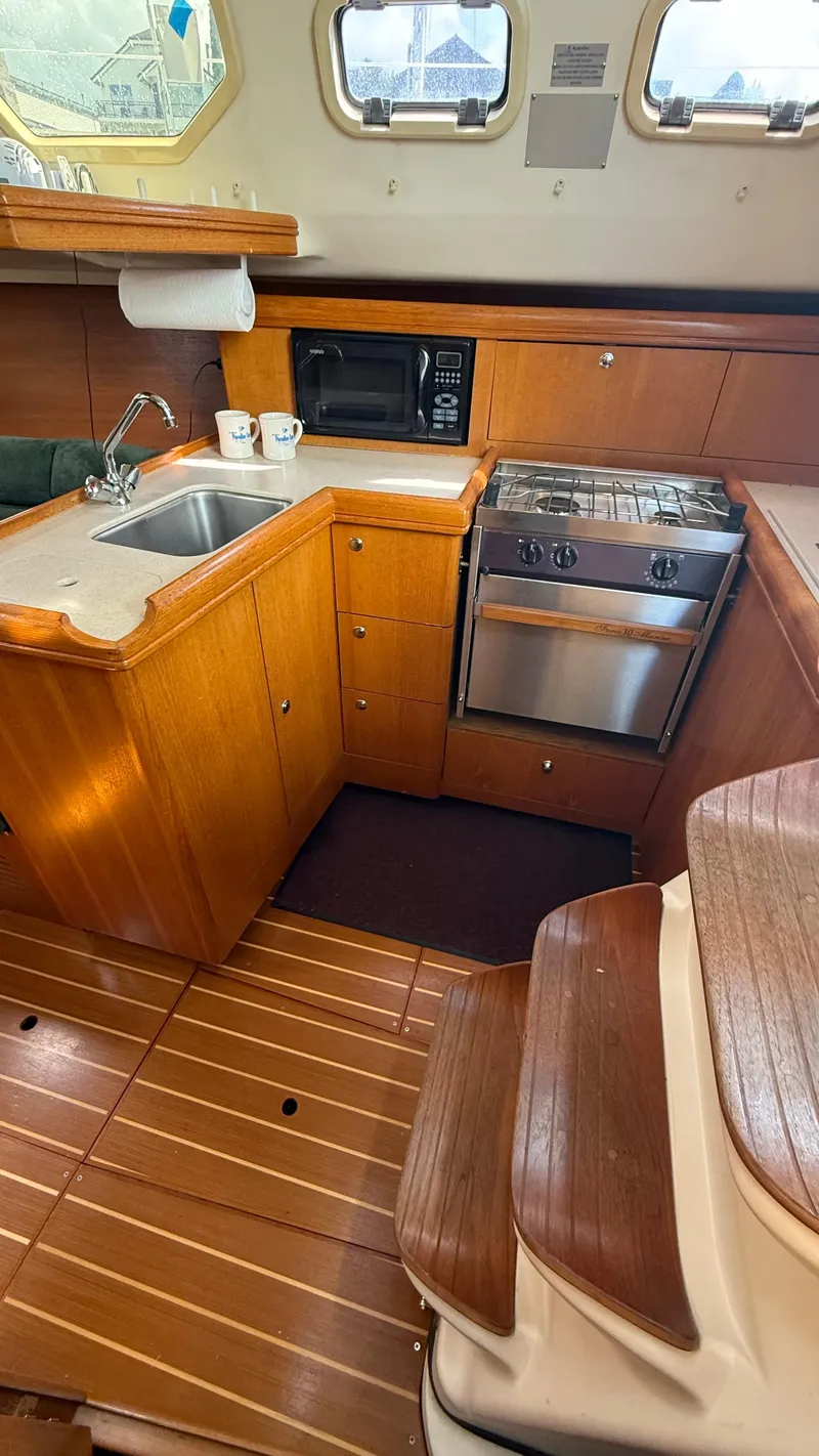 Slide: The Image of 2002 Hunter 326 yacht kitchen with wood cabinetry, sink, stove, and microwave. - 16