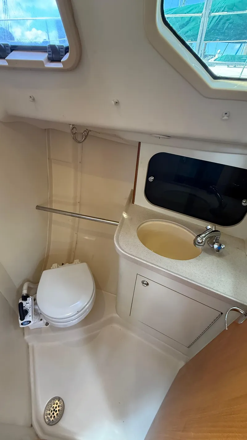 Slide: The Image of Compact bathroom in a 2002 Hunter 326 sailboat with toilet, sink, and window. - 18