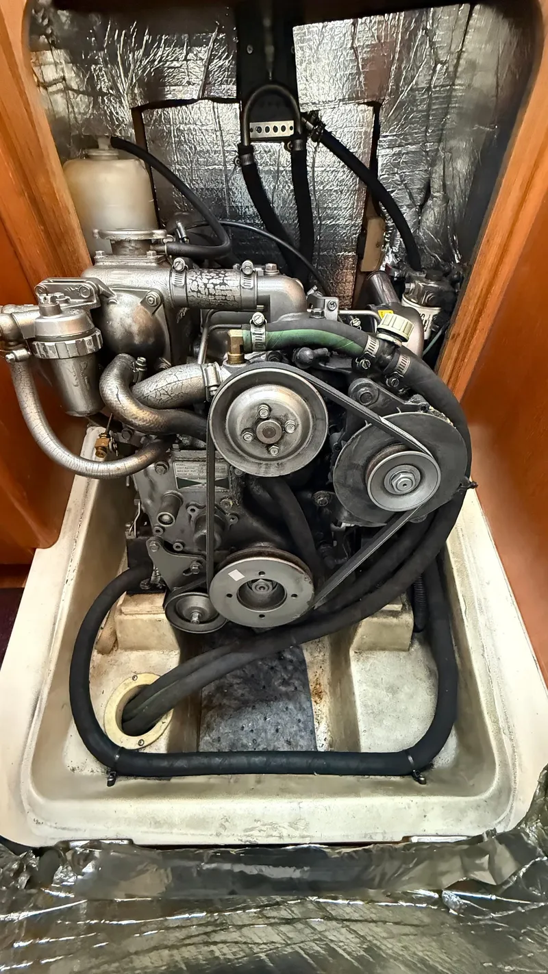 Slide: The Image of Engine compartment of a 2002 Hunter 326 sailboat, showcasing mechanical components and hoses. - 19