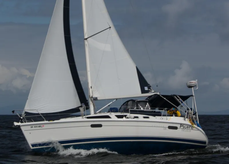 Slide: The Image of 2002 Hunter 326 sailboat navigating on open water under cloudy skies. - 2