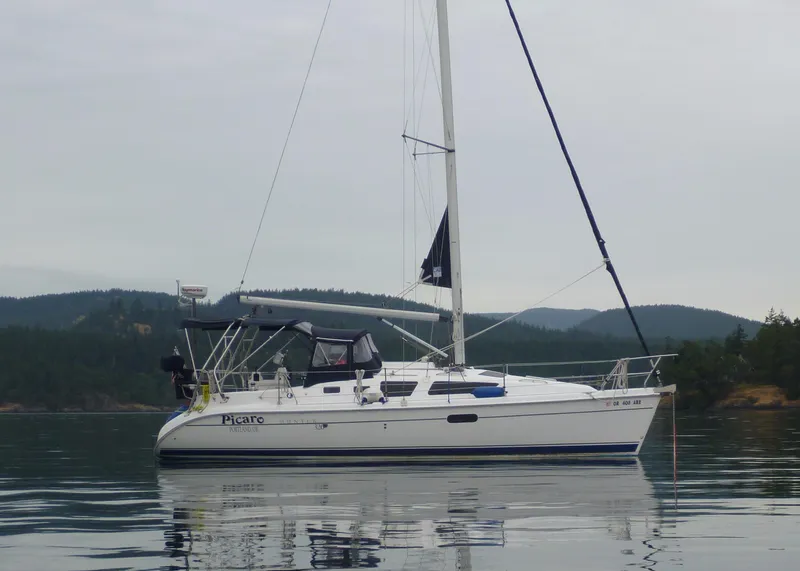 Slide: The Image of 2002 Hunter 326 sailboat on calm water with forested hills in the background. - 22
