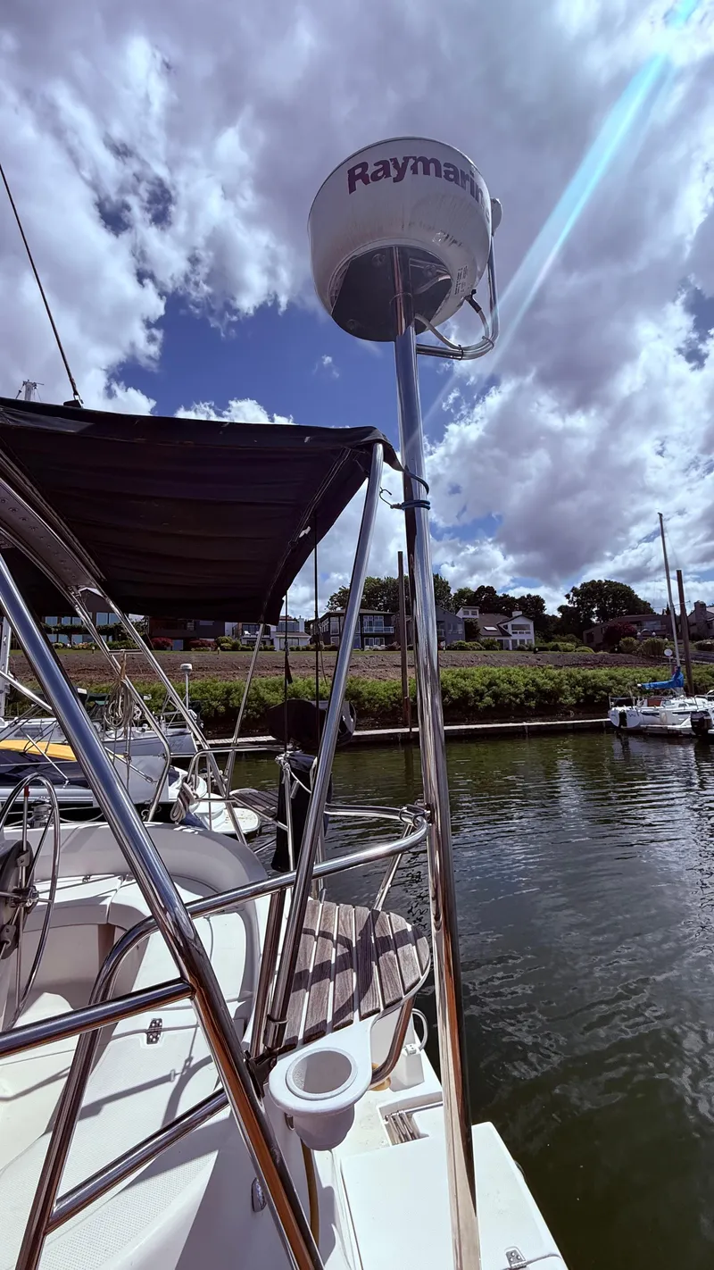 Slide: The Image of Sailboat with Raymarine radar, Hunter 326 model, docked by a scenic waterfront, under cloudy sky. - 34