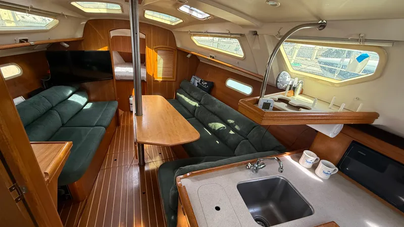 Slide: The Image of Interior of 2002 Hunter 326 sailboat with cozy seating, wooden table, and kitchenette. - 4