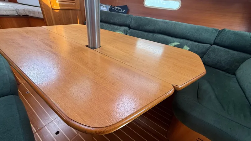 Slide: The Image of Interior of a 2002 Hunter 326 sailboat with wooden table and green seating. - 5