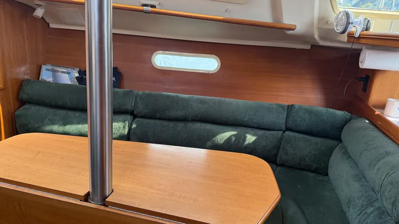 Slide: The Image of Interior of a 2002 Hunter 326 sailboat with green seating and wooden table. - 6