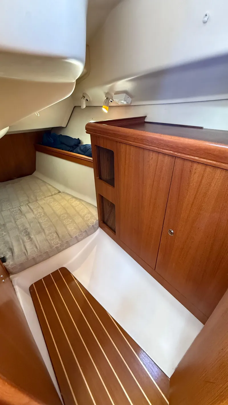 Slide: The Image of Interior cabin of 2002 Hunter 326 sailboat with wooden cabinetry and cozy sleeping area. - 9