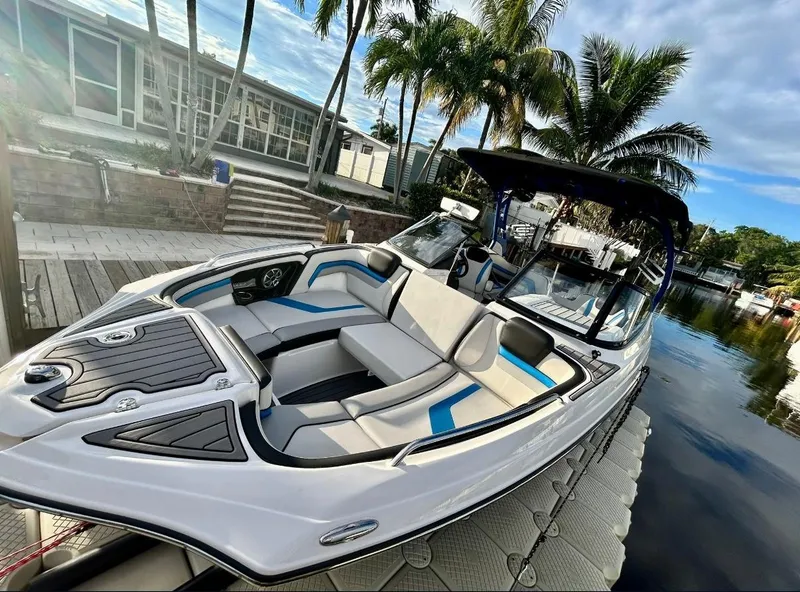 The Image of 2018 Yamaha Boats 242X E-Series docked by a scenic canal under a partly cloudy sky. - 0