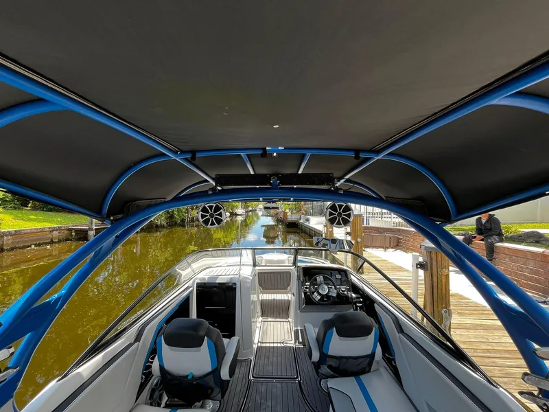 Slide: The Image of 2018 Yamaha Boats 242X E-Series interior with blue accents, docked by a canal. - 10