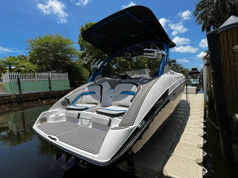 Slide: The Image of 2018 Yamaha Boats 242X E-Series docked, featuring sleek design and spacious seating under a clear blue sky. - 13