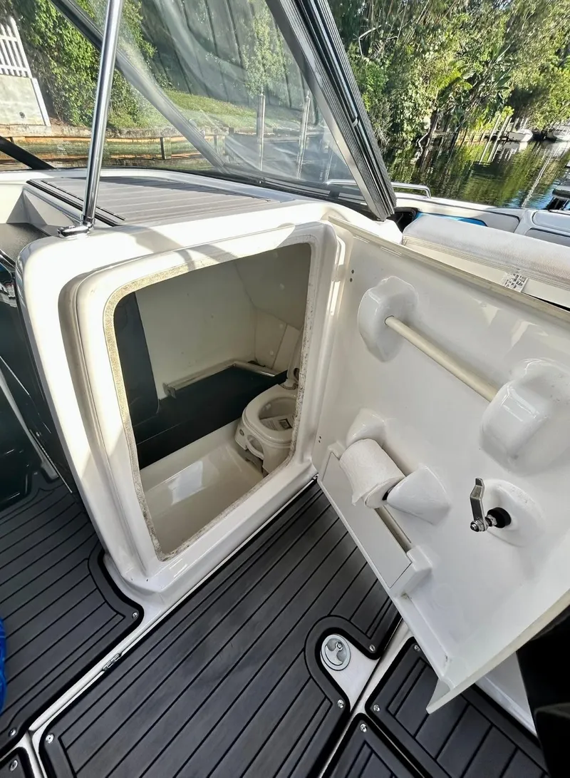 Slide: The Image of 2018 Yamaha Boats 242X E-Series interior with open compartment and toilet. - 18