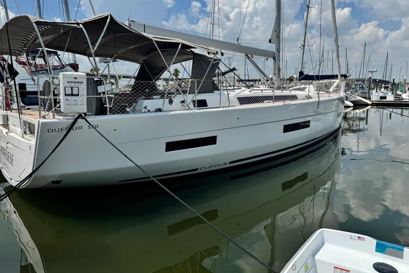 Slide: The Image of 2023 Dufour 530 yacht docked in marina, featuring sleek design and spacious deck. - 2