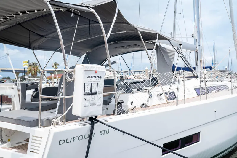 Slide: The Image of 2023 Dufour 530 yacht docked, featuring spacious deck and safety equipment. - 4