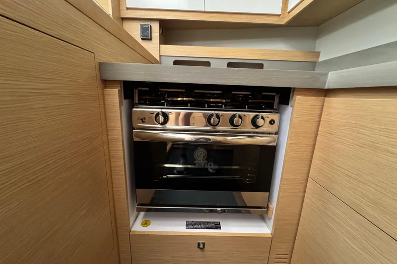 Slide: The Image of Modern kitchen oven in 2023 Dufour 530 yacht, featuring sleek wooden cabinetry. - 41