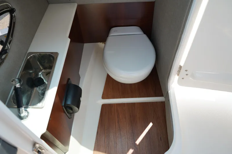 Slide: The Image of 2020 Chaparral 257 SSX boat bathroom with sink and toilet, featuring wood flooring. - 19