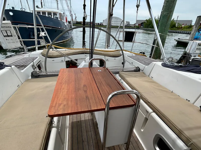 Slide: The Image of Cockpit of 2003 Beneteau First 47.7 sailboat with wooden table and cushioned seating. - 10