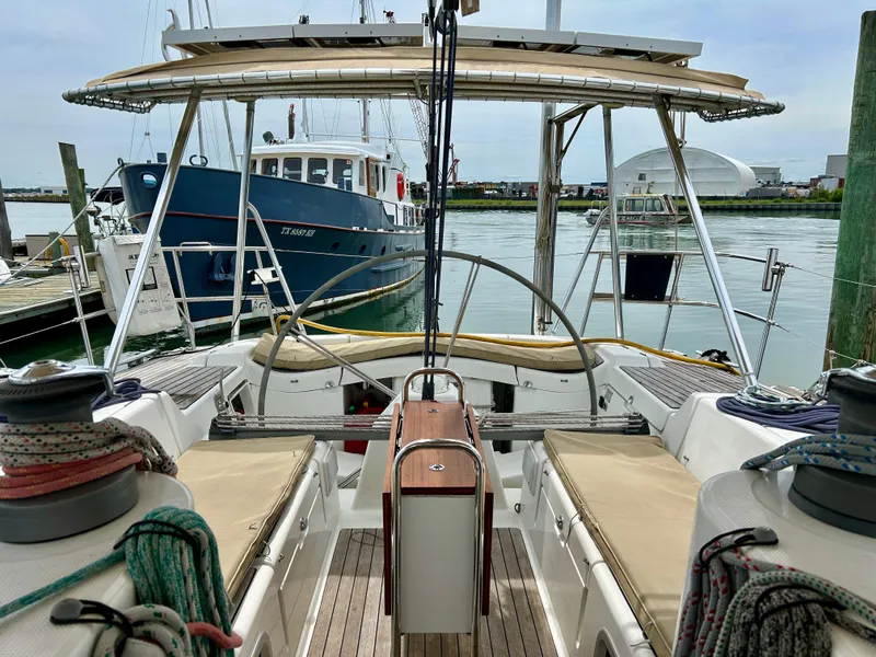 Slide: The Image of Beneteau First 47.7 sailboat cockpit, 2003 model, docked in a marina with nearby boats. - 13