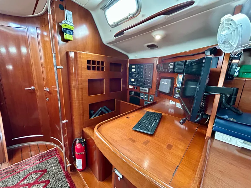 Slide: The Image of Navigation station inside 2003 Beneteau First 47.7 sailboat, featuring wood finish and control panels. - 16