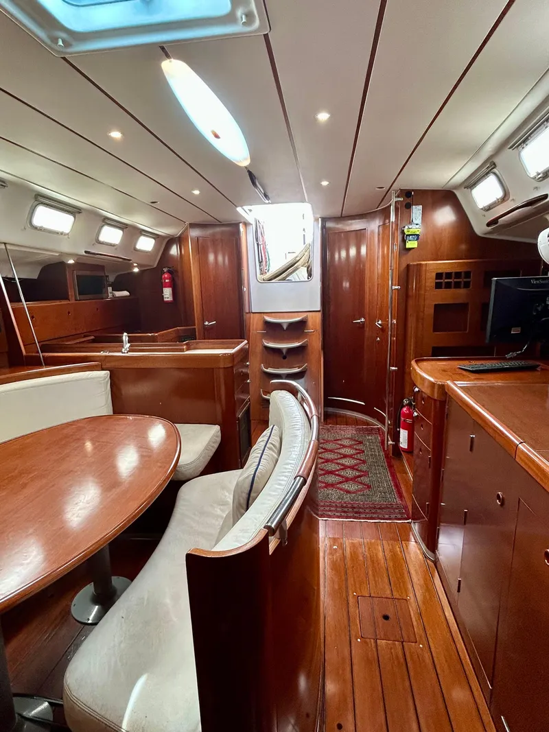 Slide: The Image of Interior of 2003 Beneteau First 47.7 yacht, featuring wood finishes and cozy seating. - 21