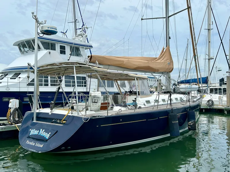 Slide: The Image of 2003 Beneteau First 47.7 sailboat docked in marina, featuring blue hull and tan sail cover. - 3