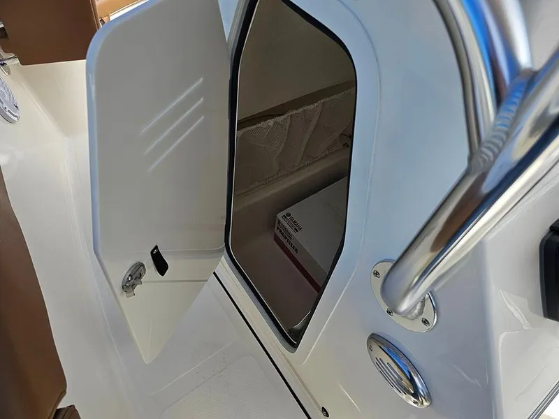 Slide: The Image of 2025 Pioneer 202 Islander boat storage compartment with open door and chrome handle. - 20