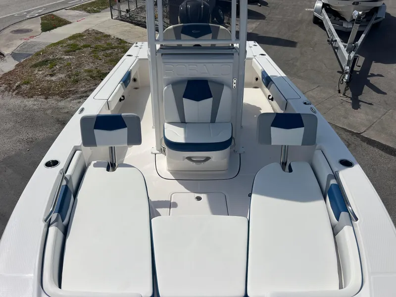Slide: The Image of 2025 Robalo 226 Cayman boat interior with white and blue seating, docked outdoors. - 12