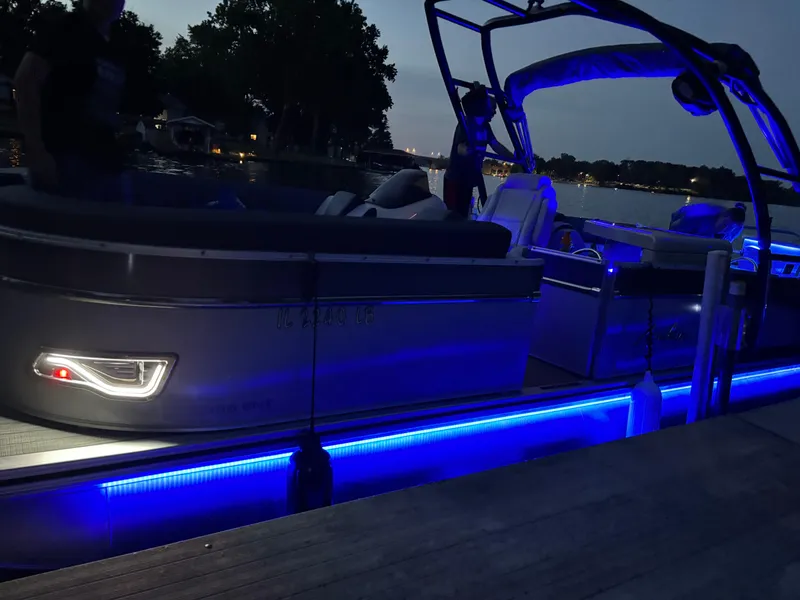 Slide: The Image of 2021 Avalon Catalina Entertainer boat with blue LED lights at dusk on a lake. - 4